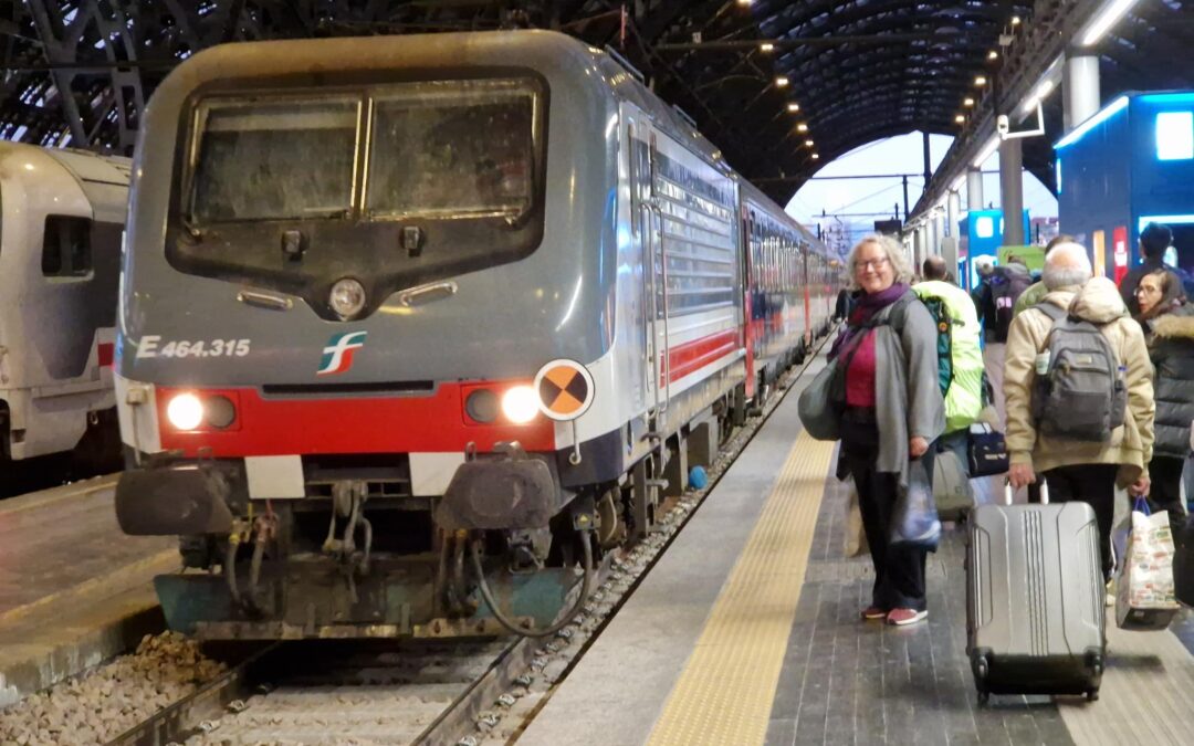 Die Lock des Nachtzugs nach Sizilien im Bahnhof von Mailand und eine erwartungsvolle, vollbepackte Reisende davor